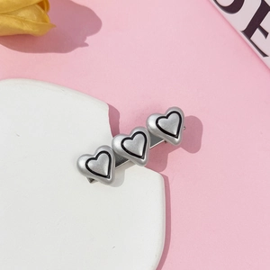 Close-up of silver triple heart hair clip with matte finish and black outline on stone base