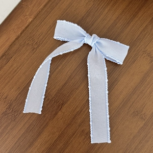 Sweet ballet style light blue mesh bow hair clip with wavy ball edge on wood background