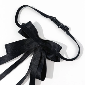 Detail of black satin bow tie featuring layered ribbon texture and adjustable strap