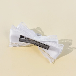 Barrette à cheveux nœud en dentelle blanche avec ruban satin et strass sur fond jaune