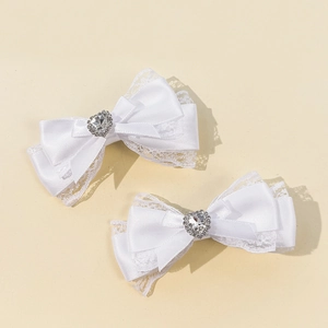 Détail de barrettes en satin blanc et dentelle avec strass en cœur pour filles