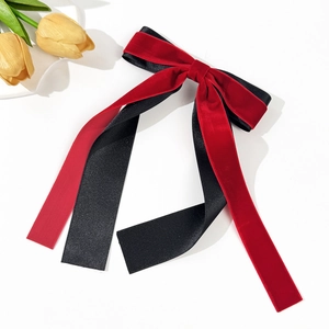 Détail des couches de velours rouge et satin noir sur une pince à cheveux double nœud