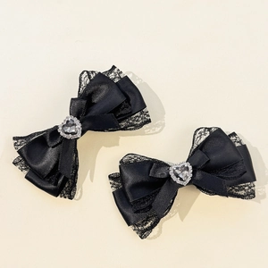 Détail de barrettes noeuds en satin noir avec dentelle et strass en forme de coeur