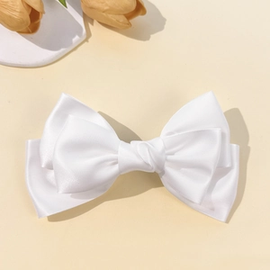 Close-up of white satin bow hair clip showing smooth fabric texture and layered design