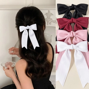 Macro detail of large bow hair clips in four colors showing ribbed texture and scalloped edges
