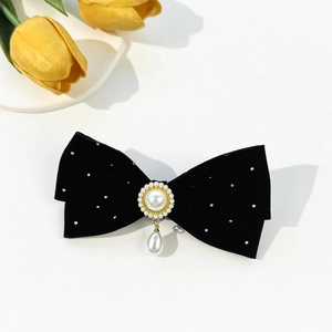 Détail d'une pince à cheveux en velours noir avec fleur de perle et pendentif goutte