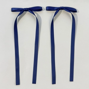 Dettaglio di un paio di fiocchi di raso blu scuro con lunghi nastri eleganti su sfondo grigio