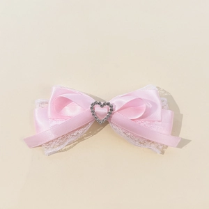 Detalle de pinza para pelo con lazo de satén rosa con encaje y diamantes de corazón