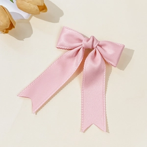 Elegant pale pink satin bow hair clip with swallowtail ribbons on a minimalist background