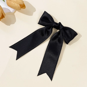 Detail of elegant black satin bow hair clip with silky texture and serrated edges