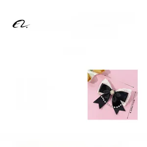 Detail of black satin bow hair clip with white lace trim and pearl bead pendant