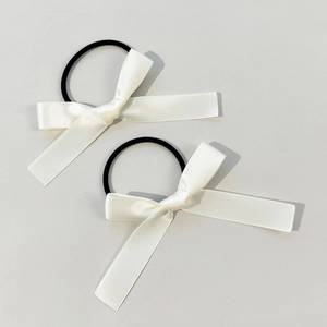 Close-up of white satin bow hair ties with elastic bands in a set of two pieces