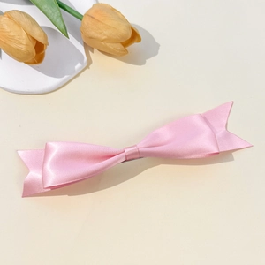 Elegant light pink satin bow hair clip on a minimalist background with tulips