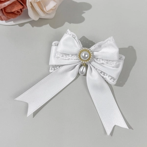 Detailed close-up of a white satin bow hair clip with lace trim and elegant pearl pendants