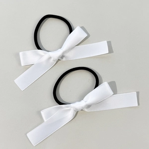 Close-up of two white satin ribbon bow hair ties with high-elastic bands for styling