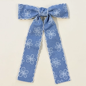 Détail d'un nœud à cheveux en denim avec motifs floraux et bords en dentelle festonnée