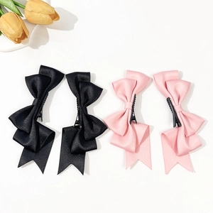 Set di quattro fermagli per capelli con fiocchi di raso rosa e neri con nastri lunghi su bianco