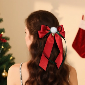 Christmas red bow hair clip with white pom-poms and gold bell on long wavy hair