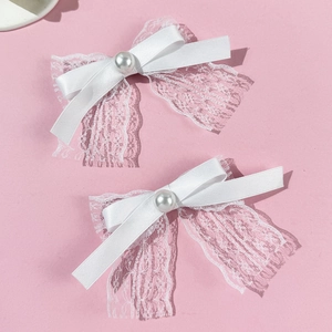 Lot de deux barrettes à nœuds en dentelle blanche avec perles sur un fond rose doux