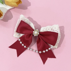 Detail of red satin and lace bow hair clip with pearl pendant and rhinestone centerpiece