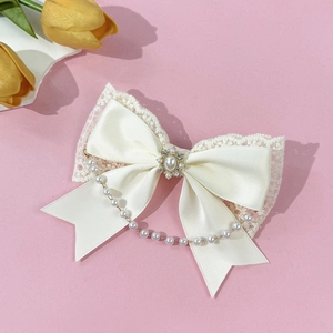 Detail of cream lace bow hair clip with oval pearl center and hanging bead chain