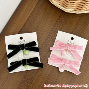 Detail of velvet bow hair clips with cat eye bead pendants in pink and green colors