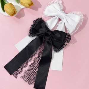 Detail view of elegant satin bow hair clips with delicate lace edges in black and white