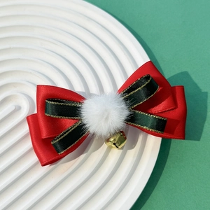Detail of Christmas bow hair clip with red satin, green ribbon, fur ball, and gold bell