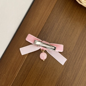 Detail view of pink velvet bow hair clip with duckbill clip and hanging bead charm