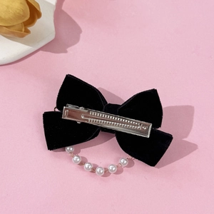 French vintage velvet bow hair clip with pearl chain detail on a pink background