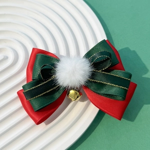 Detail of Christmas bow hair clip with red ribbon, green gold trim, pom pom and bell