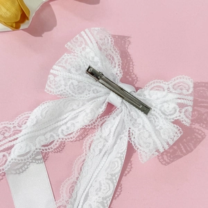 Elegant white lace bow hair clip with metal crocodile clamp on a pink background