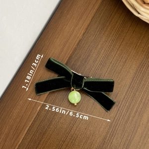 Detail view of a green velvet bow hair clip with faux jade bead and size dimensions