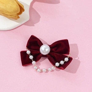 Elegant burgundy velvet bow hair clip with vintage pearl chain tassels on a pink surface