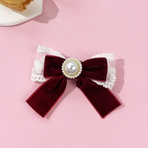 Macro shot of burgundy velvet bow hair clip with white lace trim and faux pearl detail