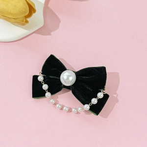 Detail of dark green velvet bow hair clip with a large pearl and delicate pearl chain