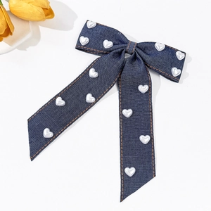 Détail d'un nœud à cheveux en denim avec perles en cœur et surpiqûres orange contrastées