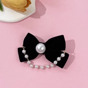 Detail of black velvet bow hair clip with a large center pearl and elegant hanging chain