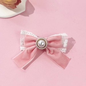 Close-up of velvet bow hair clip with white lace trim and pearl center detail