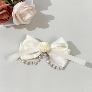 Detail einer weißen Schleifen-Haarspange aus Satin mit Rose und Perlen-Quasten