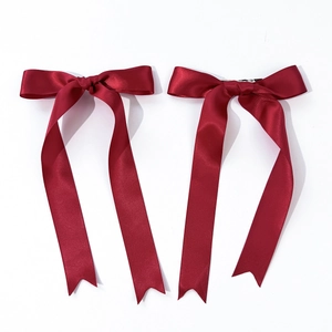 Detail view of a pair of deep wine red satin ribbon bow hair clips with long streamers