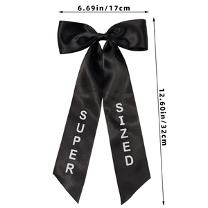 Detail view of a large black satin bow hairclip with dimensions 17cm by 32cm and printed text