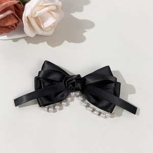 Detailansicht der schwarzen Satin-Schleife mit Rosenblüte und hängenden Perlenquasten