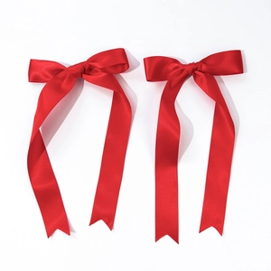 Macro detail of red satin ribbon hair bow clips with long double streamers for women