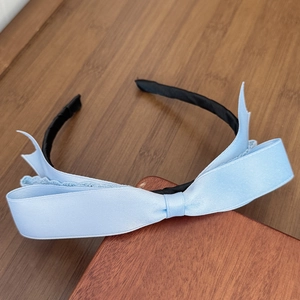 Close-up of a light blue satin bow headband on a vintage wooden background