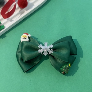 Détail d'une pince à cheveux nœud de Noël vert avec Père Noël et flocons de neige