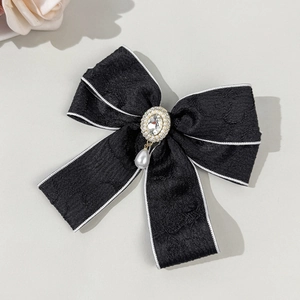 Detailed view of black jacquard bow hair clip with rhinestone and pearl drop charm
