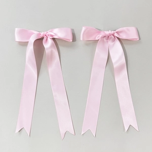 Detailed close-up of pink satin ballet ribbon hair clips with elegant long fishtail streamers