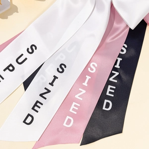 Detailed macro view of elegant silk satin hair ribbons with minimalist letter printing