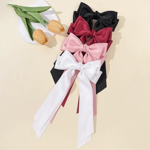 Elegant satin bow hair clips in multiple colors with long streamers on beige background